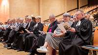 In einem Saal sitzen Soldaten und Kirchenvertreter in der ersten Reihe nebeneinander.