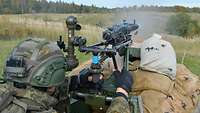 Soldat hockt im Gelände hinter Sandsäcken und schießt mit dem Maschinengewehr MG3 mit Feldlafette.