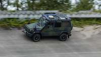 Ein Geländewagen Wolf 2 fährt in einer Steilkurve auf einer asphaltierten Fahrbahn.