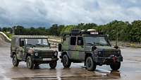 Zwei Geländewagen Wolf 1 und Wolf 2 stehen nebeneinander auf einer asphaltierten Fläche.