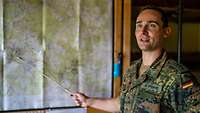 Ein Soldat zeigt mit einem Stab auf eine Lagekarte