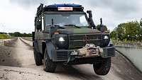 Ein Geländewagen Wolf 2 fährt auf einer asphaltierten Fahrbahn mit Wellen