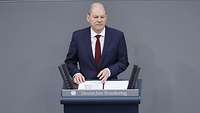 Ein Porträt von Kanzler Scholz, der am Rednerpult im Bundestag spricht.