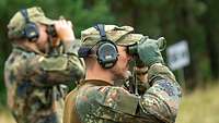 Zwei Soldaten schauen mit Ferngläsern ins Gelände.