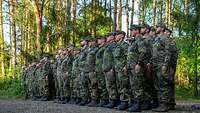 Dutzende Soldaten sind auf einer Waldlichtung in Formation angetreten.