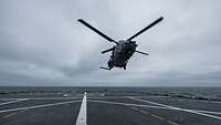 Ein Bordhubschrauber hebt vom Deck eines Schiffes ab