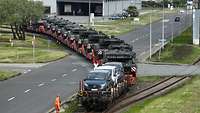Several vehicles are loaded onto railway wagons