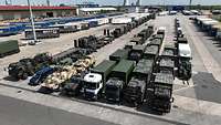 Several vehicles are parked in a large parking area at the port