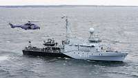 Ein Hubschrauber der Bundespolizei nimmt einen Patienten von einerm Marineschiff auf.