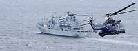 Ein Hubschrauber der Polizei im Anflug auf eine Marineschiff in See.