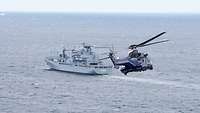 Ein Hubschrauber der Polizei im Anflug auf eine Marineschiff in See.