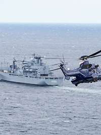 Ein Hubschrauber der Polizei im Anflug auf eine Marineschiff in See.