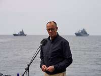 Ansprache Bundeskanzler Ein Mann spricht in ein Mikrofon, im Hintergrund sind Schiffe der Deutschen Marine in See.