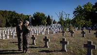 Zwei Militärdekane beten auf einem Friedhof