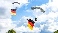 Zwei Fallschirmspringer mit Deutschlandfahnen bei der Landung