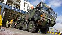 Große Bundeswehrfahrzeuge werden von einer Schiffsrampe geladen.