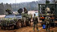 Soldaten betanken ein getarntes Spähfahrzeug mit ihrem Tankwagen.