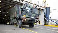 Ein militärischer Lkw fährt über eine Laderampe von einem Schiff.