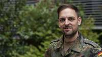 Portraitfoto eines Soldaten vor einem Busch