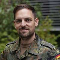 Portraitfoto eines Soldaten vor einem Busch