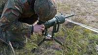 Ein Soldat kniet am Boden und richtet eine Panzerabwehrrichtmine aus