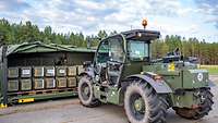 Ein militärischer Gabelstapler hebt eine Holzpalette mit grünen Munitionsbehältern 