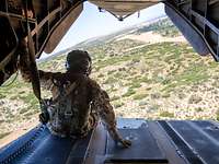 Air Centric Personnel Recovery Operatives' Course (APROC) Ein Soldat sitzt auf der Rampe eines fliegenden Hubschraubers.
