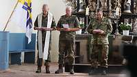 Zwei Soldaten und ein Pfarrer vor einem Altar.