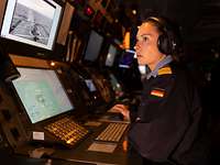 Eine Soldatin sitzt vor einer Computerkonsole in der Operationszentrale eines Kriegsschiffs.