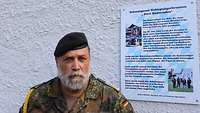 Ein Soldat mit Bart und schwarzem Barett schaut ernst in die Kamera.