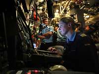 Eine Soldatin sitzt vor einer Computerkonsole in einem U-Boot