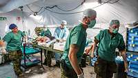 Ein verwundeter Soldat wird auf einer Trage liegend von vier Soldaten aus dem OP der Role 2 getragen