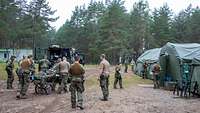 Mehrere Soldaten tragen einen Verwundeten von einem Fahrzeug in die Role 2