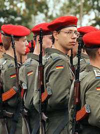 Mehrere Soldaten stehen mit Gewehren zum Appell angetreten in Reihen nebeneinander