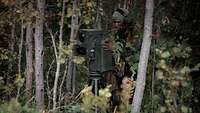 Ein Soldat steht an einem Beobachtungsgerät im Wald