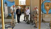Ein Soldat erzählt anderen Soldaten und zwei Zivilisten etwas über das Camp