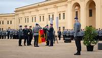 Ein Soldat befestigt ein Fahnenband an einer Dienstflagge.