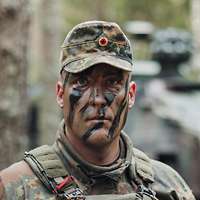 Soldat steht vor einem Gefechtsfahrzeug im Wald.