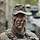 Soldat steht vor einem Gefechtsfahrzeug im Wald.