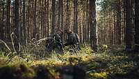 Soldaten installieren Sicherungsmittel im Wald zur frühzeitigen Bewegungserkennung.