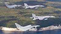 Zwei F-15 und zwei Eurofighter fliegen in Formation vor der Kreideküste an der Ostsee.