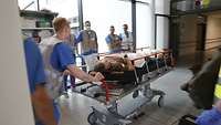 A wounded person is pushed across a corridor on a stretcher.