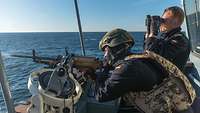 Ein Soldat schießt in See mit einem Maschinengewehr auf Seeziele.