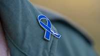 Eine blaue Schleife am Revers einer Uniform.