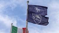 An Fahnenmasten wehen die Flaggen von Italien, der NATO und NATO ISR Force