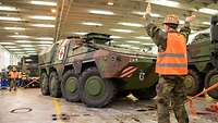 The Bundeswehr Joint Support Command Soldiers maneuver armored vehicles with red crosses on a ship's deck.