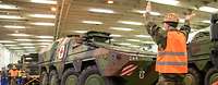  Soldiers maneuver armored vehicles with red crosses on a ship's deck.