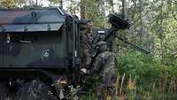 Zwei Soldaten arbeiten an ihrem Fahrzeug und bauen eine Antenne auf.