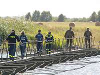 Soldaten und Zivilisten laufen über eine behelfsmäßige Metallbrücke, die über die Havel führt.