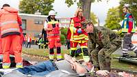 Eine Frau in Uniform hebt gerade die Trage mit einem Patienten an